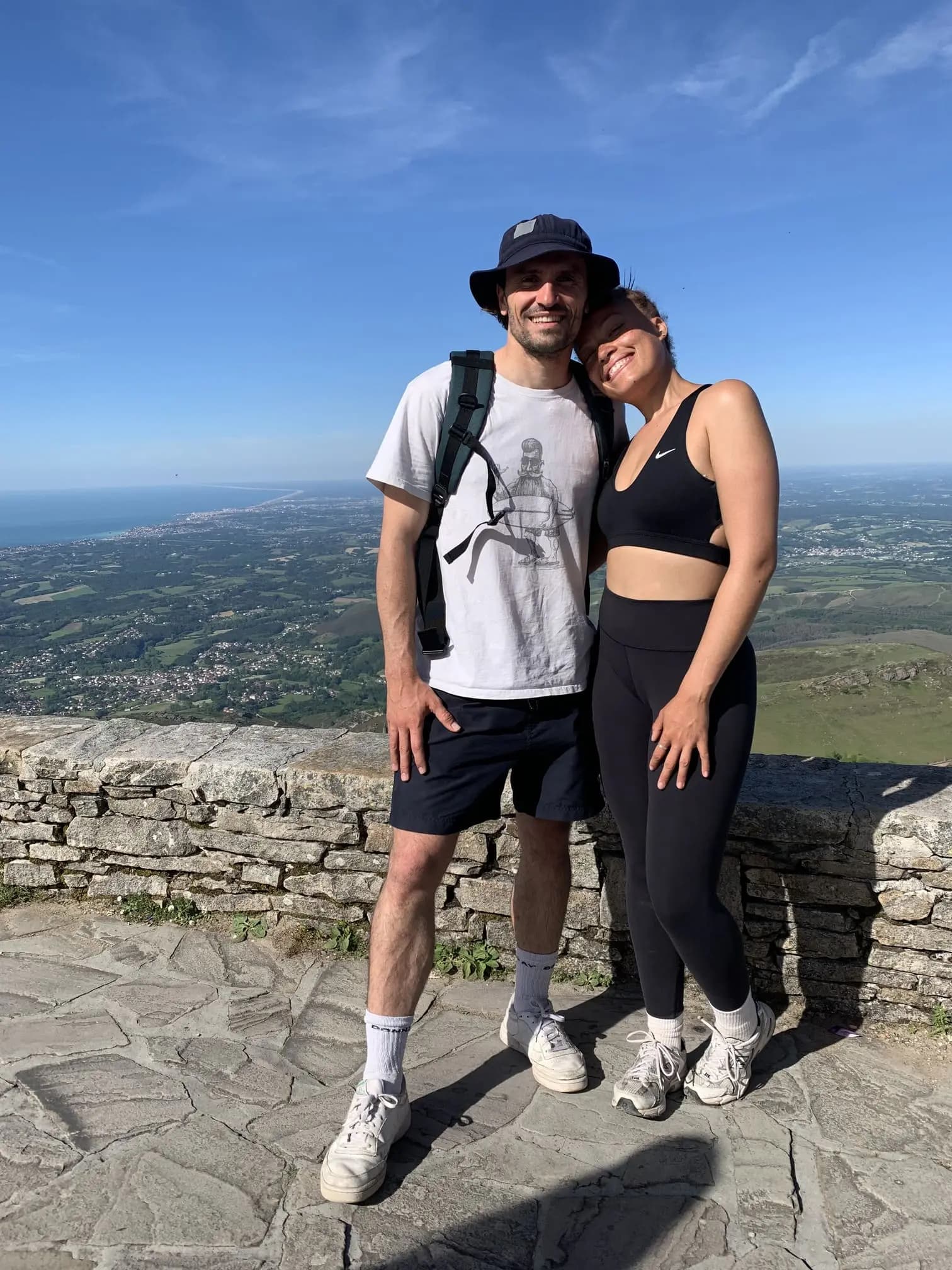 Two guides posing on a stone viewpoint high above the coastal plain and the ocean