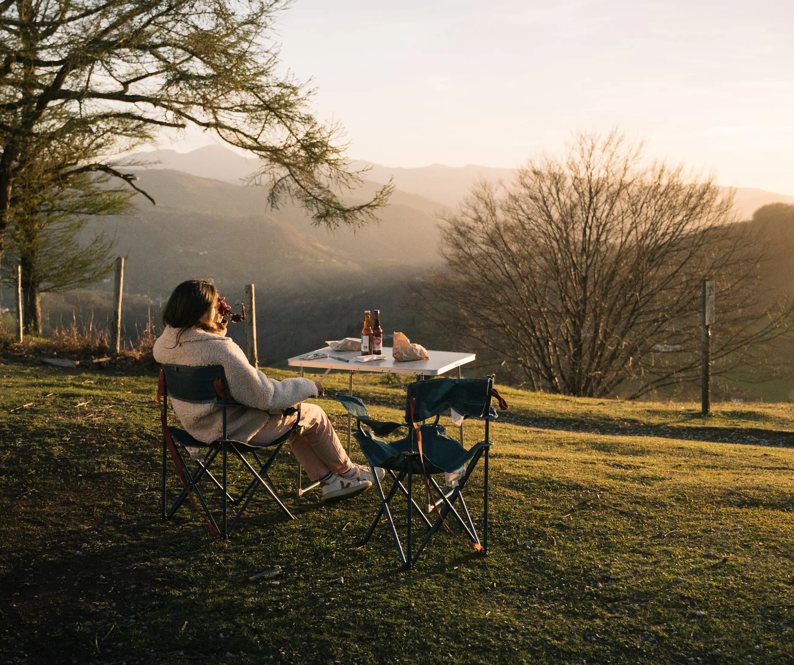 Drinks facing the mountains, with a bottle and camping chairs set out on the grass